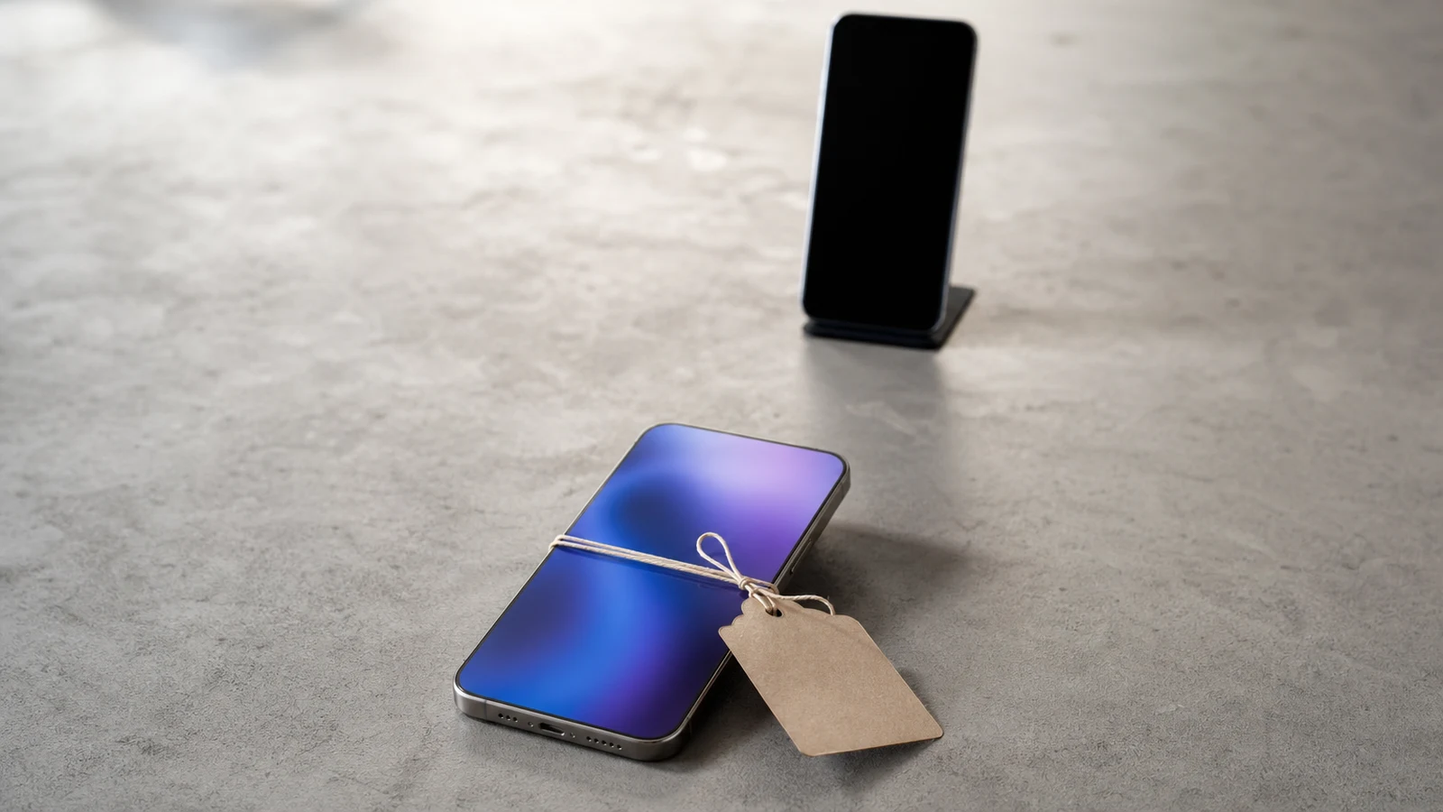 Smartphone met een leeg prijskaartje op een stenen tafel, met een tweede telefoon op de achtergrond